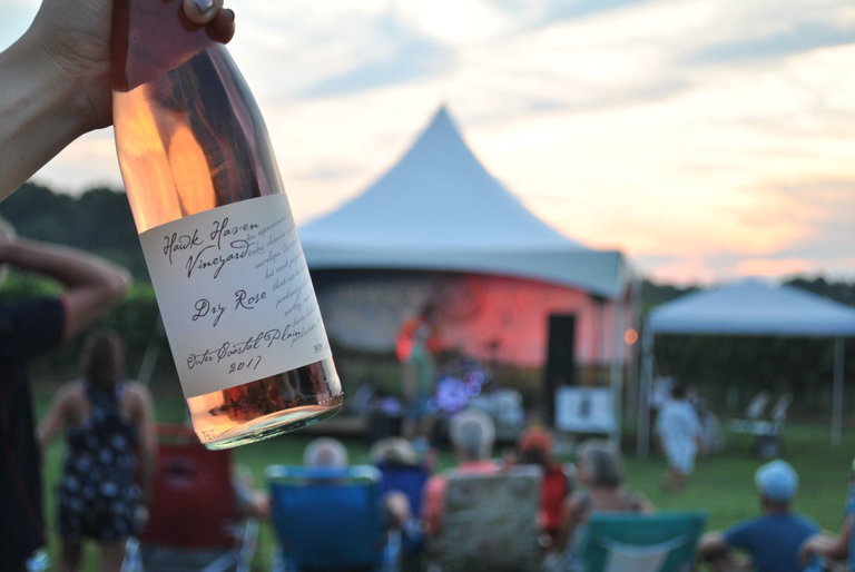 Hawk Haven Winery and Vineyard Dry Rose bottle of wine with vines and rootstock live music in background