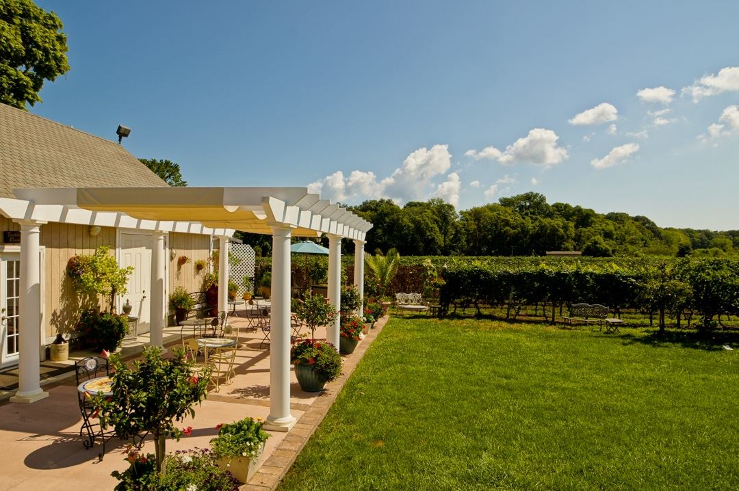 Turdo Vineyard and Winery landscaped patio with pergola next to vineyards on a sunny day.