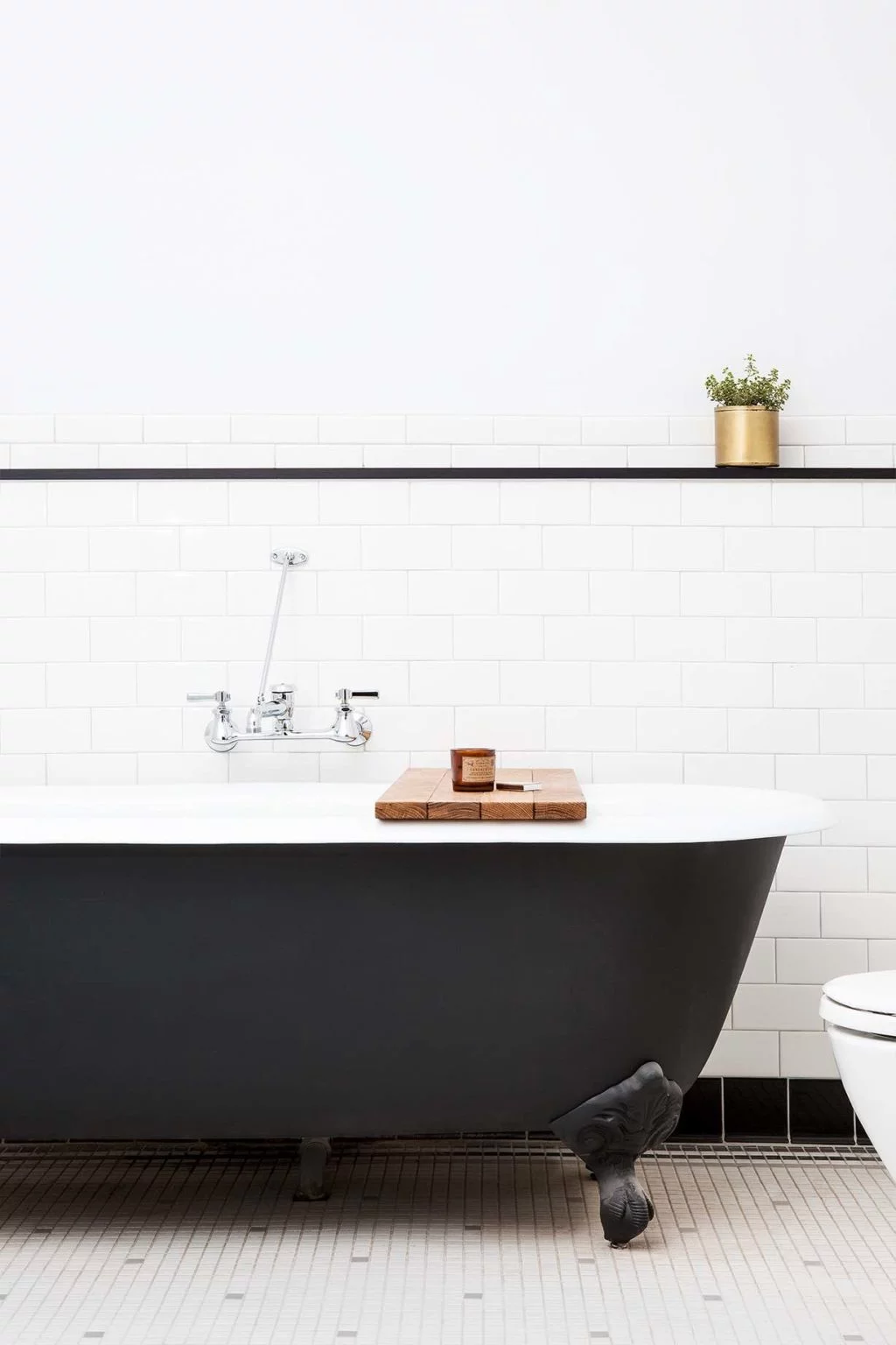 a clawfoot tub with a wooden tray and a jar on it