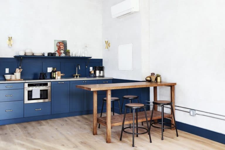A blue kitchen in the Louisa suite at Lokal Hotel Old City with brass hardware and open shelf with a handmade wooden island and table with four stools