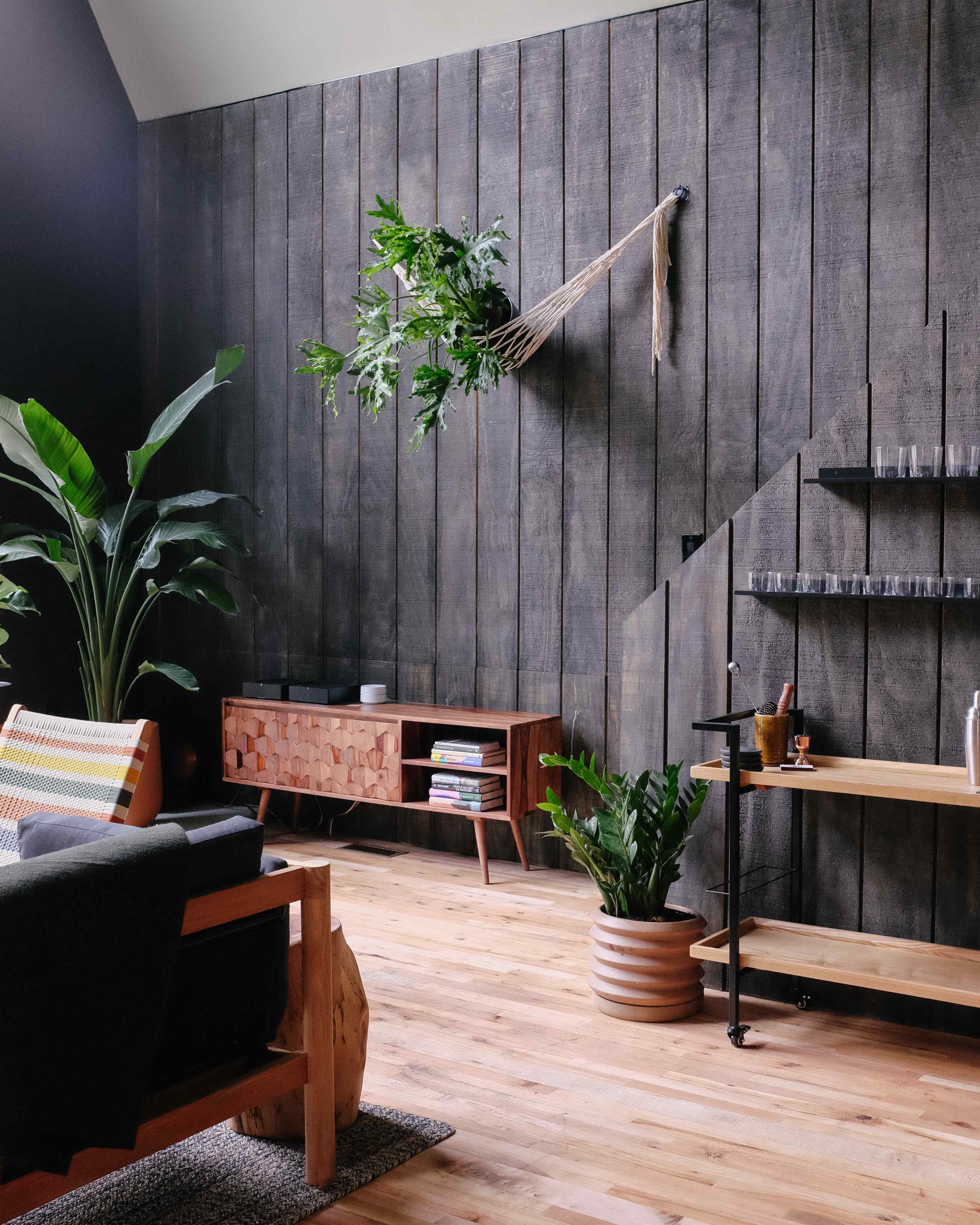 A cozy lounge area with a wooden floor, plants, and furniture.
